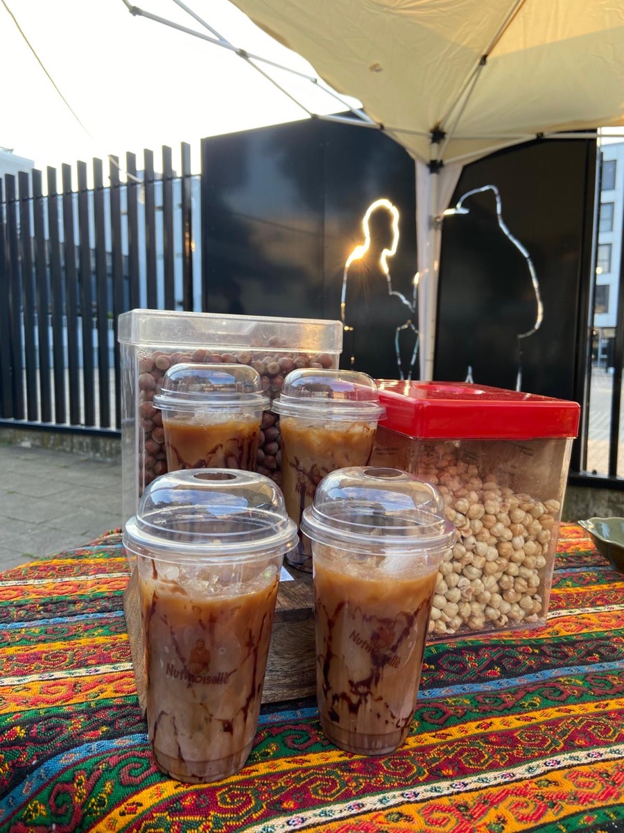 Iced Hazelnut Latte in Nutmoiselle-Bechern auf einem bunten Kelim