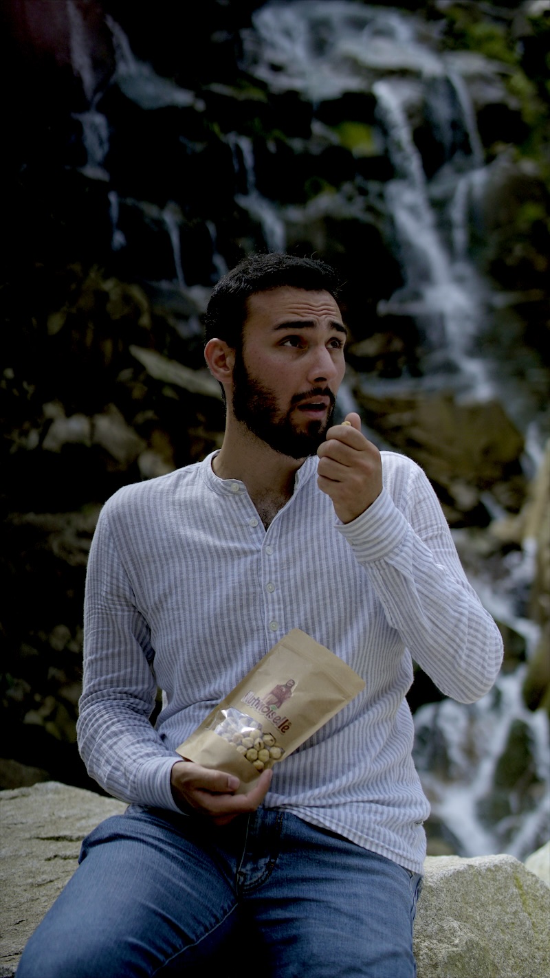Gründer Taha Kamat genießt Nutmoiselle-Haselnüsse an einem Wasserfall